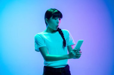 Genç Asyalı kadın portresi mavi-mor renkli gradyan stüdyo arka planında neon ışıklarıyla