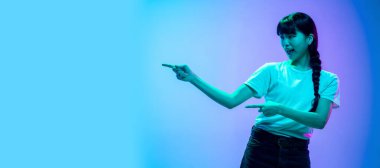 Genç Asyalı kadın portresi mavi-mor renkli gradyan stüdyo arka planında neon ışıklarıyla