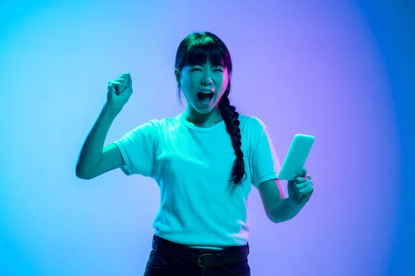 Unga asiatiska kvinnor porträtt på lutning blå-lila studio bakgrund i neon ljus — Stockfoto