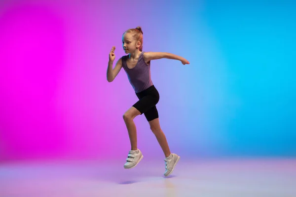 Nastolatka działa, jogging z gradientem różowo-niebieski neon studio tło w ruchu — Zdjęcie stockowe