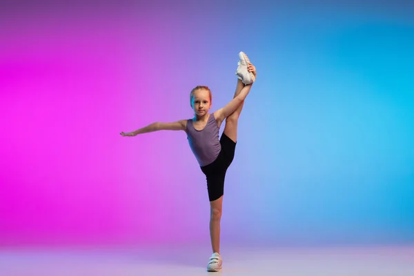 Teenagermädchen läuft, joggt gegen das Gefälle rosa-blauer Neon-Studiohintergrund in Bewegung — Stockfoto