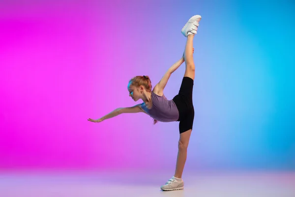 十代の女の子が実行しています,運動中のグラデーションピンクブルーネオンスタジオの背景に対してジョギング — ストック写真
