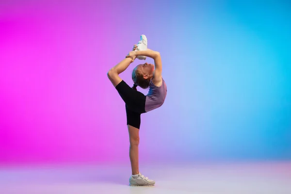 Tiener meisje lopen, joggen tegen gradiënt roze-blauw neon studio achtergrond in beweging — Stockfoto