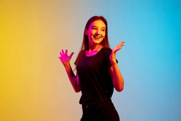 Jonge blanke vrouwen portret op gradiënt blauw-gele studio achtergrond in neon licht — Stockfoto