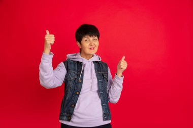 Yaşlı kadın kırmızı arka planda izole edilmiş. Teknolojik ve neşeli yaşlı yaşam tarzı konsepti