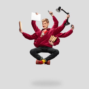 Yakışıklı çoklu kollu öğrenci gri stüdyo arka planında ekipmanla izole edilmiş.