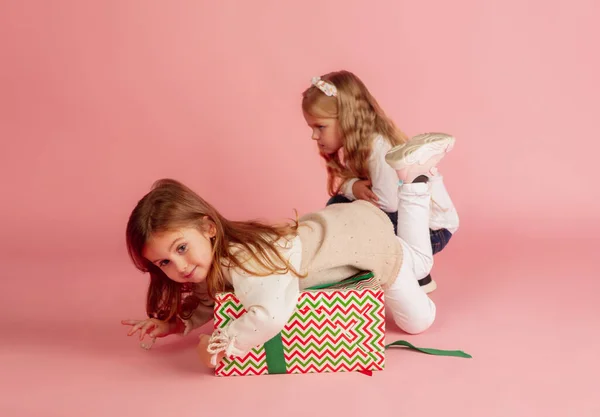 Giving and getting presents on Christmas holidays. Two little smiling children having fun isolated on pink studio background — Stock Photo, Image