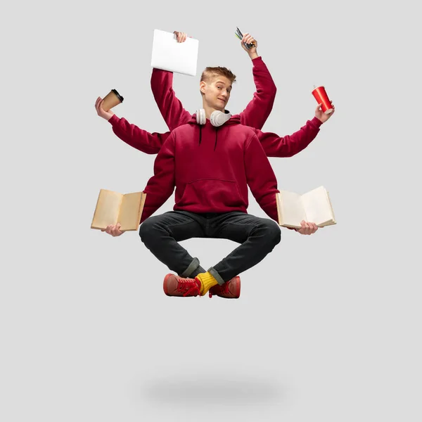 Handsome multi-armed student levitating isolated on grey studio background with equipment — Stock Photo, Image