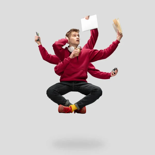 Handsome multi-armed student levitating isolated on grey studio background with equipment — Stock Photo, Image