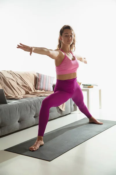 Gyönyörű fiatal nő edz otthon, jógázik a szürke szőnyegen otthon. — Stock Fotó