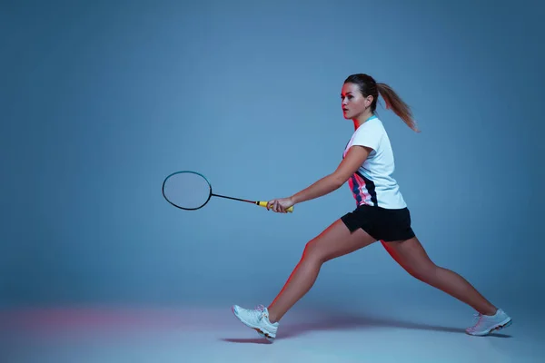 Bella donna handicappata che pratica a badminton isolato su sfondo blu in luce al neon — Foto Stock