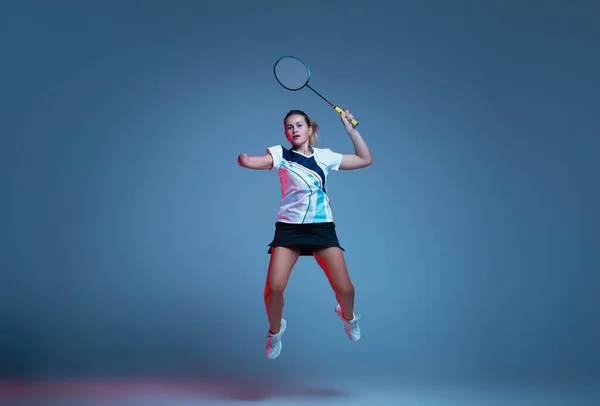 在霓虹灯下与蓝色背景隔离的羽毛球练习的漂亮残疾女子 — 图库照片