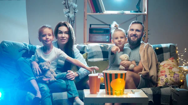 Familia feliz viendo proyector, TV, películas con palomitas de maíz en la noche en casa. Madre, padre e hijos pasando tiempo juntos. —  Fotos de Stock