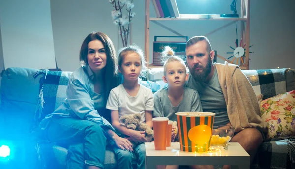 Familia feliz viendo proyector, TV, películas con palomitas de maíz en la noche en casa. Madre, padre e hijos pasando tiempo juntos. —  Fotos de Stock