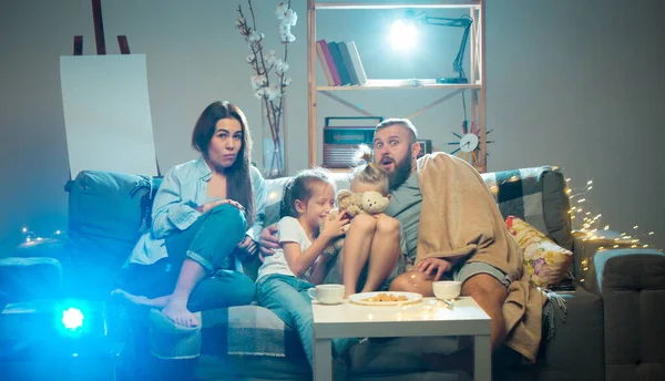 Glückliche Familie, die abends zu Hause Projektor, Fernseher, Filme mit Popcorn guckt. Mutter, Vater und Kinder verbringen Zeit miteinander. — Stockfoto