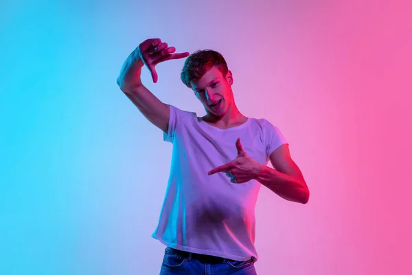 Jovens homens brancos retrato em gradiente azul-rosa estúdio fundo em luz de néon — Fotografia de Stock