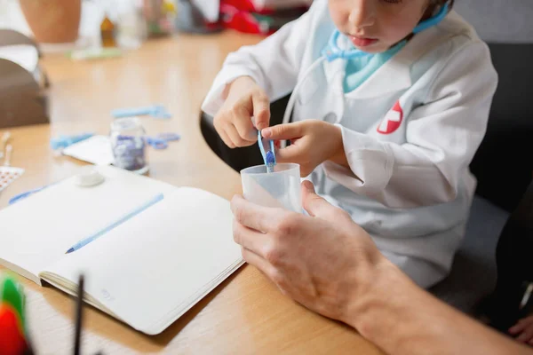 Kleine jongen spelen doet alsof als dokter onderzoeken van een man in comfortabele medische kantoor — Stockfoto