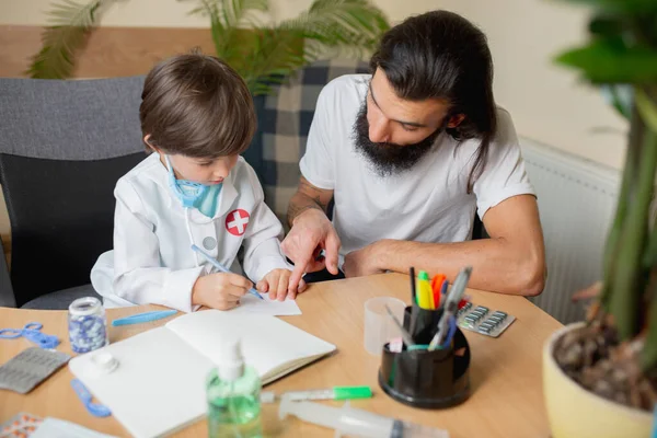 Kleine jongen spelen doet alsof als dokter onderzoeken van een man in comfortabele medische kantoor — Stockfoto