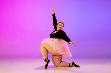 Güzel beyaz ırk artı boyut modeli neon ışıklı arka planda mor-pembe renkte bale dansı yapıyor.
