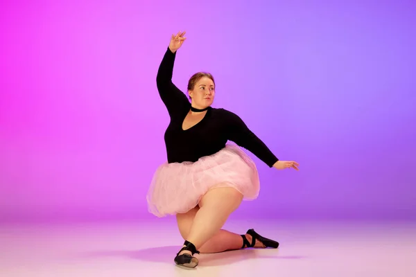 Bonito caucasiano plus size modelo praticando dança de balé em gradiente roxo-rosa estúdio fundo em luz de néon — Fotografia de Stock
