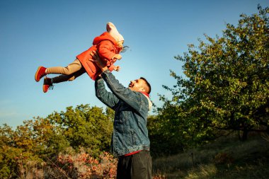 Mutlu baba ve küçük tatlı kız sonbahar güneşli bir günde orman yolunda yürüyorlar.