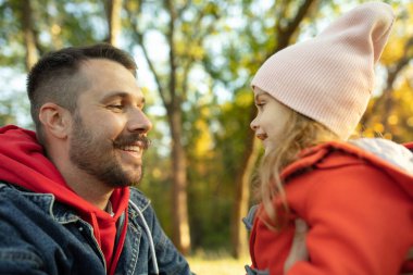 Mutlu baba ve küçük tatlı kız sonbahar güneşli bir günde orman yolunda yürüyorlar.