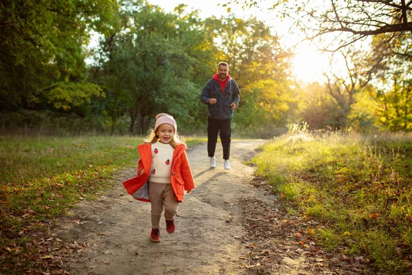 Mutlu baba ve küçük tatlı kız sonbahar güneşli bir günde orman yolunda yürüyorlar. — Stok fotoğraf