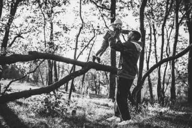 Mutlu baba ve küçük tatlı kız sonbahar güneşli bir günde orman yolunda yürüyorlar.