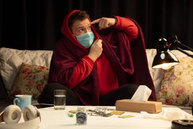 Ekoseli bir maske takmış bir adam hasta birinden korumaya çalışıyor.