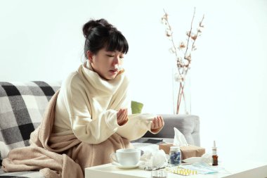 Ekoseye sarılmış bir kadın hasta, hasta, hapşıran ve öksüren bir kadın gibi görünüyor.