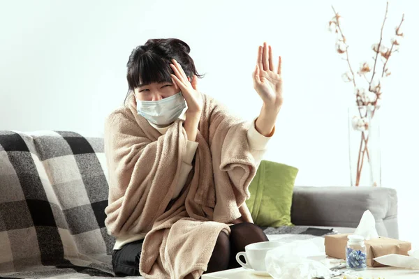 Mujer envuelta en una manta a cuadros y con mascarilla tratando de protegerse de alguien enfermo cerca — Foto de Stock