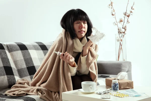 A kockás ruhába csomagolt nő betegnek, betegnek, tüsszentőnek és köhögőnek tűnik otthon ülve. — Stock Fotó