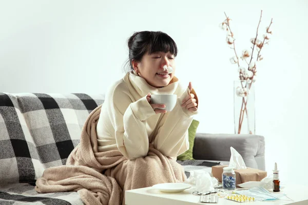 Frau im Karo sieht krank, krank, niesend und hustend aus, wenn sie zu Hause drinnen sitzt — Stockfoto