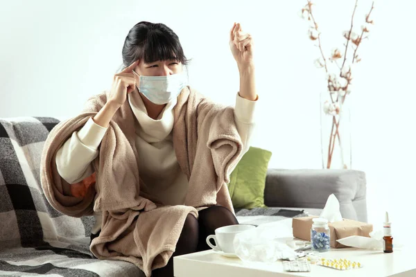 Mujer envuelta en una manta a cuadros y con mascarilla tratando de protegerse de alguien enfermo cerca — Foto de Stock