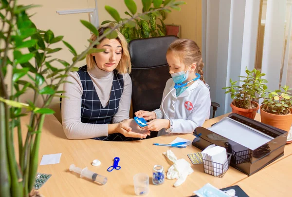 Kinderarzt untersucht ein Kind in einer Arztpraxis. Kleines Mädchen, das spielt, gibt sich als Arzt für Frau aus — Stockfoto