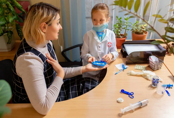 Kinderarzt untersucht ein Kind in einer Arztpraxis. Kleines Mädchen, das spielt, gibt sich als Arzt für Frau aus — Stockfoto