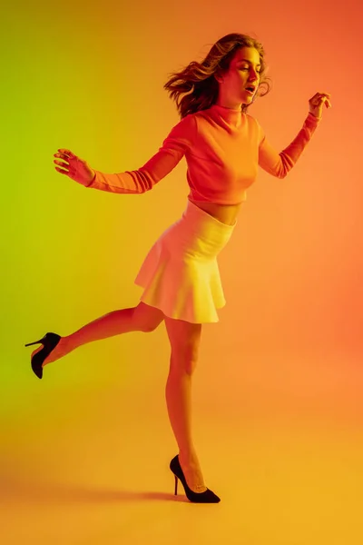 Gyönyörű csábító lány divatos, romantikus ruhát fényes gradiens zöld-narancs háttér neon fény — Stock Fotó