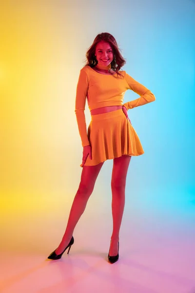 Menina sedutora bonita na moda, roupa amarela romântica em gradiente brilhante fundo amarelo-azul em luz de néon — Fotografia de Stock