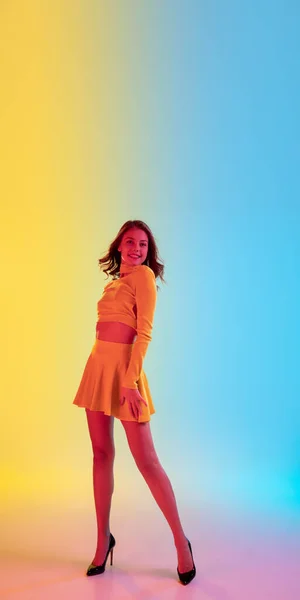 Menina sedutora bonita na moda, roupa amarela romântica em gradiente brilhante fundo amarelo-azul em luz de néon — Fotografia de Stock