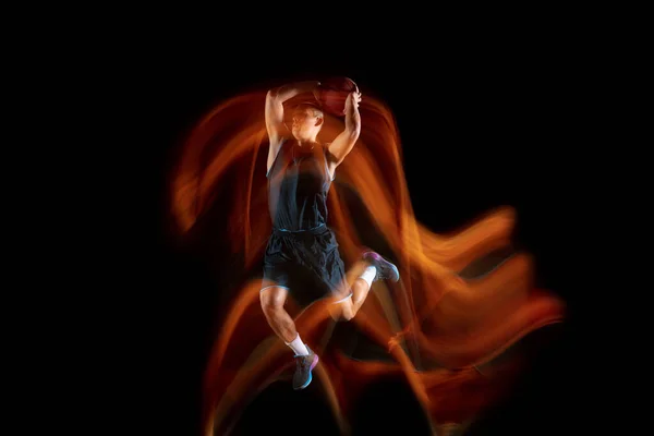 Jovem jogador de basquete asiático leste em ação e saltar em luz mista sobre fundo estúdio escuro. Conceito de esporte, movimento, energia e estilo de vida dinâmico e saudável. — Fotografia de Stock