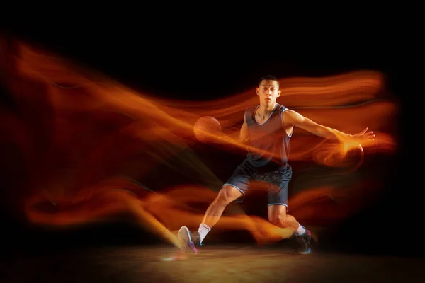 Joven jugador de baloncesto asiático oriental en acción y saltar en luz mixta sobre fondo oscuro estudio. Concepto de deporte, movimiento, energía y estilo de vida dinámico y saludable. —  Fotos de Stock