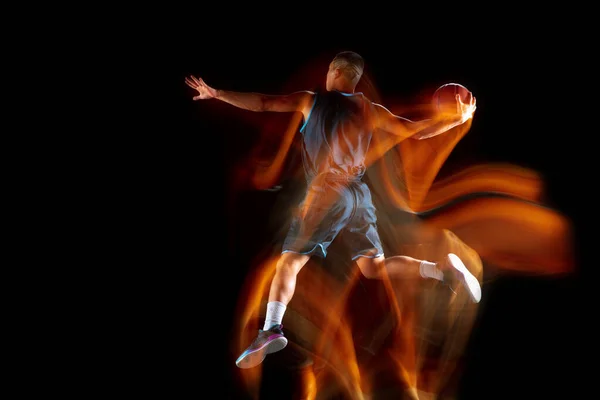 Joven jugador de baloncesto asiático oriental en acción y saltar en luz mixta sobre fondo oscuro estudio. Concepto de deporte, movimiento, energía y estilo de vida dinámico y saludable. — Foto de Stock