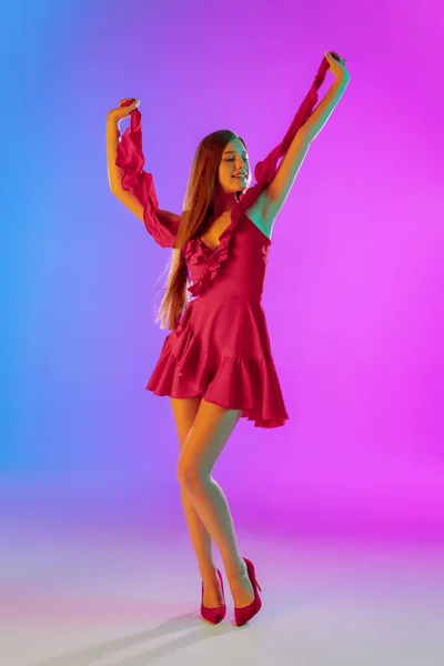 Mooi gelukkig meisje in modieuze, romantische outfit op heldere gradiënt paars-blauwe achtergrond in neon licht — Stockfoto