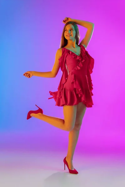 Vacker glad flicka i fashionabla, romantiska outfit på ljus lutning lila-blå bakgrund i neon ljus — Stockfoto