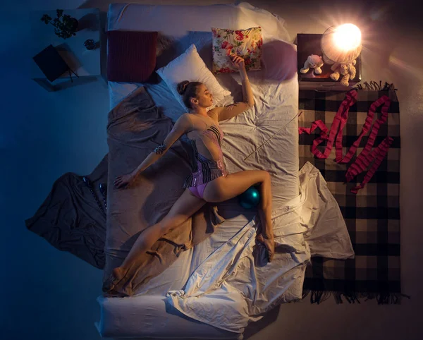 Вид спящего в своей спальне молодого профессионала в спортивной одежде с синим мячом. — стоковое фото