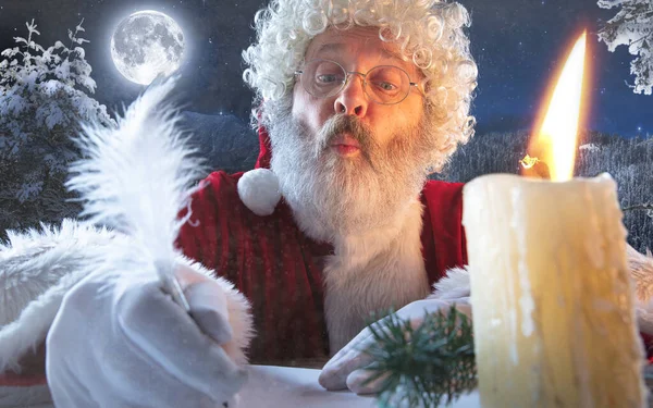 Papai Noel emocional parabenizando com Ano Novo e Natal, escrevendo uma carta, lista de desejos à meia-noite com vela — Fotografia de Stock