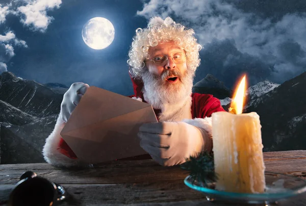 Emocjonalny Święty Mikołaj gratulując Nowego Roku i Bożego Narodzenia, wysyłając list, lista życzeń w północy ze świecą — Zdjęcie stockowe