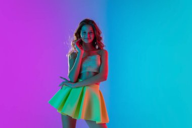 Güzel, baştan çıkarıcı bir kızın portresi şık, parlak bir elbise içinde. Renk gradyanı pembe-mavi arka planda, neon ışıklı..