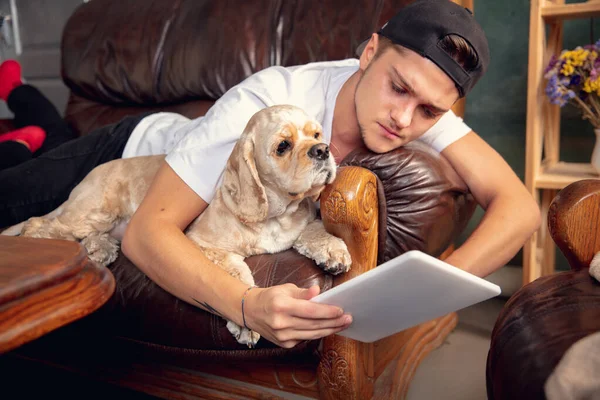 Close up young Caucasian man and his pet American Cocker Spaniel cream colour have a rest at home.