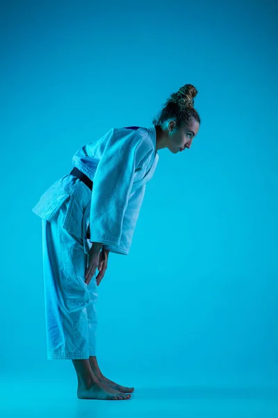 Entrenamiento judoista femenino profesional aislado en fondo de estudio azul en luz de neón. Estilo de vida saludable, concepto deportivo. — Foto de Stock